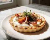 Une flammekueche alsacienne individuelle, garnie de lardons, oignons et ciboulette, sur une crème onctueuse.