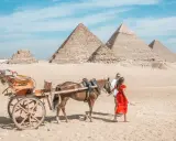 Ein Paar genießt eine Kutschfahrt durch das Kairo-Land, vorbei an den majestätischen Pyramiden unter blauem Himmel.