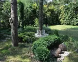Urokliwe ogród leśny aranżacje z kamiennymi kulami wodnymi, ozdobną ławką wokół drzewa i bujną zielenią.
