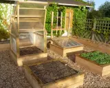 Plusieurs carrés potagers en bois, certains avec des mini-serres, prêts à fabriquer un jardin productif.