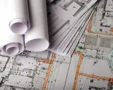 Planos arquitectónicos enrollados y apilados, listos para la construcción.