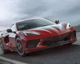 Czerwony Chevrolet Corvette C8 pędzi po drodze, jego sportowy design podkreślony przez dynamiczne linie i agresywny przód.