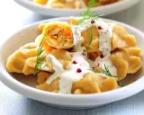Pyszne, proste dania na Święta Bożego Narodzenia: pierogi z farszem, polane sosem, ozdobione koperkiem i pieprzem.