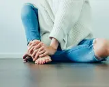 Frau mit zerrissener Jeans hält ihr Bein, das auf Schmerzen Knie Innenseite ohne Schwellung hindeutet.