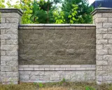 Solidne słupki ogrodzeniowe z betonu, obłożone kamieniem, tworzą elegancką całość z murem. Idealne rozwiązanie, czym obłożyć stare słupki ogrodzeniowe.