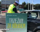 Policjant kontroluje kierowcę. Plakat informuje: "Trzeźwy za kółkiem". Co to znaczy trzeźwy? To bezpieczeństwo na drodze.