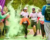 Uczestnicy biegu w kolorowym proszku, w tym 3 forma run, biegną wśród zielonej chmury.