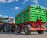 Czerwony traktor z zieloną przyczepą. Dowiedz się, jakich przyczep nie trzeba rejestrować, by swobodnie poruszać się po drogach.