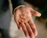 Dłoń mężczyzny trzyma dwie złote obrączki. To symbol miłości i tego, kto kupuje obrączki na ślub.
