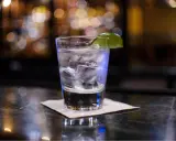 Ein erfrischender Gin Tonic mit Eis und Limette auf einer Bar.
