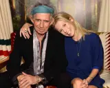 Keith Richards och en ung kvinna ler mot kameran. Hon vilar huvudet mot hans axel.