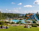 Familj njuter av en solig dag vid ett vattenland med rutschkanor och pooler, en idyllisk semester i norra Sverige.