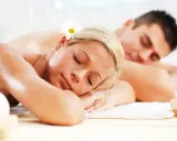 Para relaksująca się w SPA, z kwiatkiem we włosach, obok płonących świec.