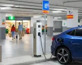 Familia comprando mientras su coche eléctrico se carga en puntos de recarga coches eléctricos en España gratis.