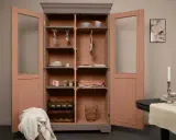 Armoire vitrée avec un relooking meuble 2 couleurs : gris anthracite et rose poudré. Elle contient vaisselle, verres, bouteilles de vin et objets déco.