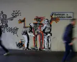 Famous graffiti depicts two police officers interacting with a skeletal figure, with a Keith Haring-esque character and a dog nearby.