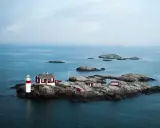 Fyren och röda hus på en klippö bland svenska öar.