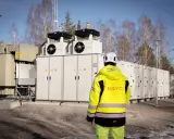 En person i gul jacka står framför en stor fristående batterilagring.