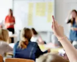 Schülerin hebt die Hand, um eine Frage zu stellen. Vielleicht fragt sie, mit welcher Note man eine 5 ausgleichen kann.