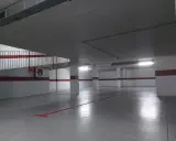 Un garaje particular recién pintado, con líneas rojas en el suelo y paredes blancas con franjas rojas.