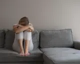 Kobieta z depresją siedzi skulona na kanapie, przygotowując się do komisji lekarskiej ZUS. Co mówić, by uzyskać pomoc?