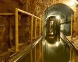 Podziemny tunel z wodą i żółtymi poręczami, idealny na zwiedzanie kopalni.