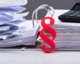 Stosy dokumentów, paragraf symbolizujący prawo pracownika i kalkulator.