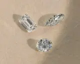 Tre diamanti di taglio diverso (smeraldo, marquise, rotondo) su sfondo chiaro, pronti per la classificazione diamanti.