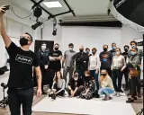 Grupa entuzjastów fotografii na zajęciach w szkole fotografii. Uczestnicy pozują do wspólnego zdjęcia w studiu.