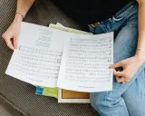 Osoba w dżinsach przegląda nuty. Może to tekst piosenki "Malik Montana Wuwua"?
