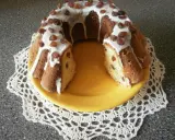 Pyszna babka drożdżowa z rodzynkami, polana lukrem i ozdobiona bakaliami, prezentuje się apetycznie na żółtym talerzu.