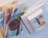 Pieniądze i gniazdko elektryczne symbolizują rozliczenie z PGE po inwestycji w fotowoltaikę.