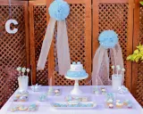 Mesa dulce bautizo casera con pastel, galletas y cupcakes decorados en tonos azules.
