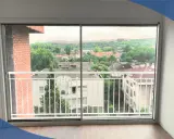 Amplio ventanal de cristal con cámara de aire, con vistas a un paisaje urbano y montañoso. Balcón con barandilla blanca.