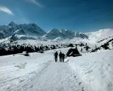 Trzej turyści idą szlakiem przez zasypane śniegiem Tatry. Widok idealny na tatry zimą dla średniozaawansowanych.