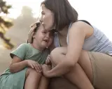 Madre consola la figlia che piange, un abbraccio che mostra le diverse tipologie di attaccamento sicuro e amorevole.