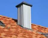 Moderner Schornstein mit Verlegemuster auf Ziegeldach. Das Schiefer-Muster der Dachziegel ist gut erkennbar.