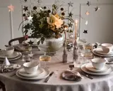 Vacker nyårsdukning med guldiga stjärnor, ljus och blommor. En elegant dukning för en festlig kväll.