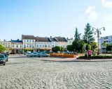 Rynek w Krapkowicach z kolorowymi kamienicami i brukowaną nawierzchnią. Atrakcje miasta widoczne w tle.