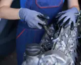 Mecánico con guantes trabajando en un motor, mostrando componentes como inyectores y partes del cigüeñal.