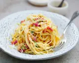 Pyszna carbonara ze śmietaną, okraszona boczkiem i parmezanem, czeka na widelcu.