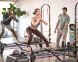 Persone che praticano pilates su reformer, un allenamento che migliora forza e flessibilità.