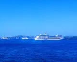 Grandi navi da crociera Royal Caribbean navigano in acque blu, con isole sullo sfondo.