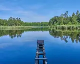Drewniane pomosty na spokojnym jeziorze, otoczonym zielonym lasem. Idealne miejsce na wypoczynek nad wodą na Pojezierzu Palowickim.
