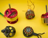Vergleich von brushed und brushless Motoren: zwei komplette Motoren und zwei freigelegte Spulen mit Kupferwicklungen auf gelbem Hintergrund.