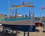 Un bateau hors de l'eau, prêt pour la maintenance, avec le nom "MARSEILLE" peint sur sa coque. Le drapeau français flotte au loin.