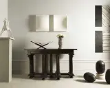 En elegant inredning med en skulptur av Claes Dahlen, en öppen bok, blommor i en vas och mörka stenägg.
