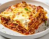 En saftig bit lasagne med lager av köttfärssås, béchamelsås och nybakade lasagneplattor, toppad med smält ost och persilja.