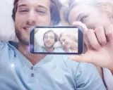 Para widzi na ekranie telefonu siebie, uśmiechnięci i blisko. To piękne objawy zauroczenia.