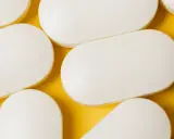 Bianche compresse ovali, disposte su sfondo giallo. Potrebbero essere un antibiotico azitromicina, utili per combattere infezioni batteriche.